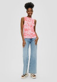 Roze bloemenpatroon mouwloze top met een rechte zoom, gecombineerd met lichtblauwe wijd uitlopende jeans en crèmekleurige sandalen.
