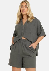 Grå tvådelad outfit bestående av en kortärmad skjorta med knappar och bröstficka samt matchande shorts med elastisk midja. Texturerat tyg.