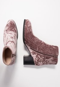 Stivali alla caviglia in velluto rosa polveroso con zip laterale, tacco a blocco e superficie testurizzata, caratterizzati da una silhouette aderente e punta rotonda.