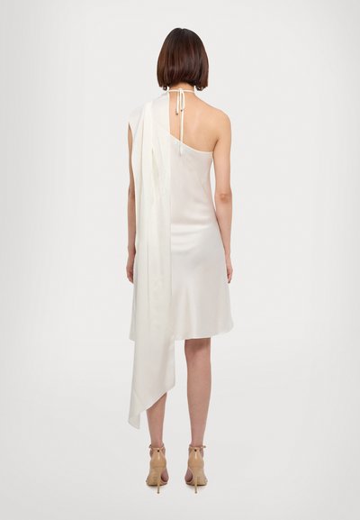 White, sleeveless dress with a single shoulder strap and a draped accent. Smooth fabric with a fluid cut, featuring a back tie closure.