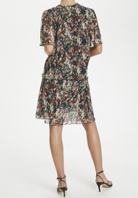 Blumenbedrucktes Kleid aus leichtem, transparentem Stoff mit kurzen Ärmeln und einem gestuften Rock. Dominante Farben sind Marineblau, Pink und Grün.