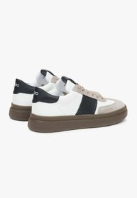 Białe i czarne sneakersy z akcentami z jasnego zamszu, okrągły nosek, sznurowana konstrukcja, gumowa podeszwa i logo na pięcie.