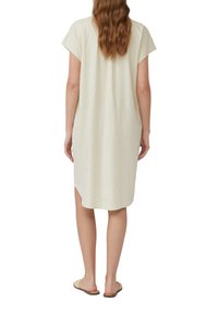 Helles beige Leinenkleid mit kurzen Ärmeln, lockerer Passform, knielang, mit seitlichen Schlitzen, glatter Textur, getragen mit flachen Sandalen.