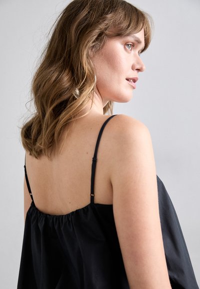 Haut en tissu noir avec une coupe décontractée et des bretelles réglables fines. Le dos présente des détails froncés près de l'encolure. Texture lisse.