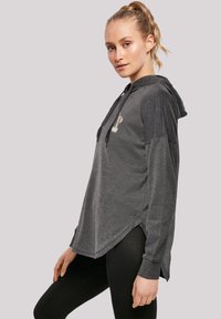 Sudadera con capucha gris, de mangas largas, dobladillo curvado y diseño gráfico frontal. Fabricada con una tela suave y de corte relajado.
