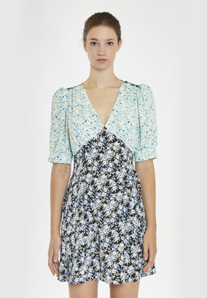 Kwiatowa sukienka z jasnoniebieską górą z krótkimi bufiastymi rękawami, dekoltem w kształcie litery V oraz czarną spódnicą ozdobioną białymi i niebieskimi wzorami kwiatowymi.