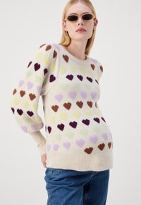 Maglione lavorato a maglia con una base crema e motivi a cuore testurizzati in marrone, viola, giallo e verde. Maniche e orlo a coste.