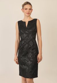 Abito nero senza maniche con scollatura a V, motivo floreale testurizzato, lunghezza al ginocchio e silhouette aderente. Tessuto liscio con una leggera lucentezza.