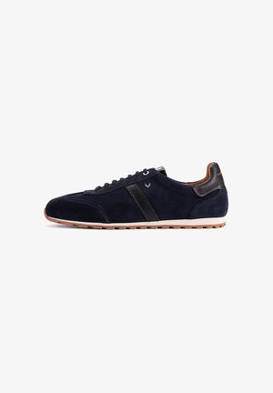 Zapatilla deportiva de ante azul marino con detalle de cuero negro, forro interior marrón, suela blanca y suela exterior de goma, vista lateral.