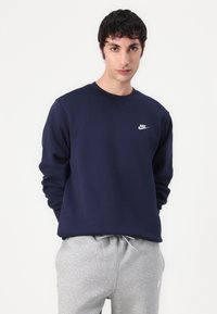 Marineblauw Nike sweatshirt met lange mouwen en een ronde hals; heeft een klein wit logo op de borst. Zacht, textuurstof.