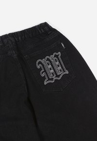 Black denim pants featuring an elastic waistband and a back pocket with white embroidered detail. Smooth texture with a classic cut.