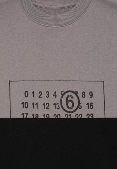 Pullover grigio e nero con scollatura a girocollo; presenta una griglia numerica in stile bingo stampata e il numero "6" in un contorno circolare sul petto.