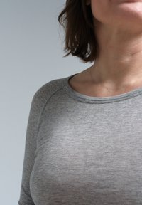 Graues geripptes Langarmshirt mit rundem Ausschnitt, das eine glatte Textur und subtile Stickdetails entlang des Kragens und der Ärmel aufweist.