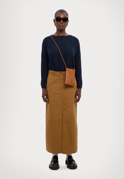 Suéter de punto con estampado de la marina, falda maxi de algodón marrón, bolso cruzado de mimbre marrón y zapatos de plataforma negros. Los accesorios incluyen gafas de sol.