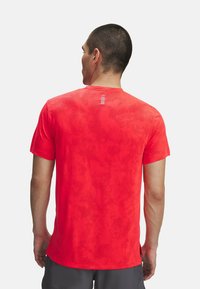 Camiseta deportiva roja con un patrón texturizado, cuello redondo, mangas cortas y un diseño sutil en la parte posterior que presenta rayas horizontales.