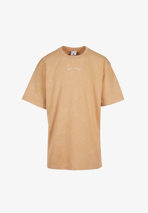 Lühikeste varrukatega üleraskes t-särgis, mis on valmistatud heledast pruunist puuvillast, on õrnalt pleekinud tekstuur ja valge logo rinnal.