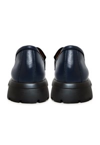 Marinblå läderskor med rund tå, kontrasterande svart gummisula och minimala sömnadsdetaljer på baksidan.