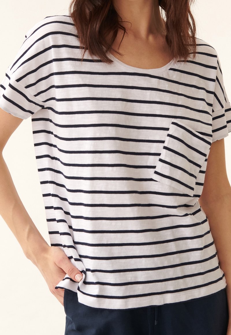 T-shirt en coton rayé avec des rayures horizontales bleu marine et blanches, col rond, manches courtes et une poche poitrine sur le côté gauche.