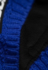 Blue knitted fabric with a ribbed texture next to a smooth black fleece, featuring a clean design focused on warmth and comfort.