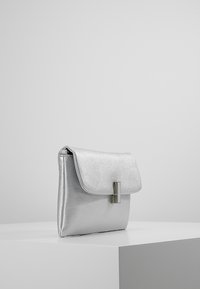 Silver metallic clutch bag with a textured finish, rectangular shape, flap closure, and a rectangular metal accent on the front.