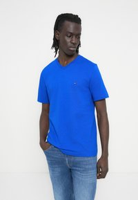 Μπλε μπλουζάκι με V λαιμόκοψη από βαμβάκι με κοντά μανίκια. Διαθέτει μικρό λογότυπο στο στήθος και άνετη εφαρμογή. Συνδυάζεται με τζιν παντελόνι.