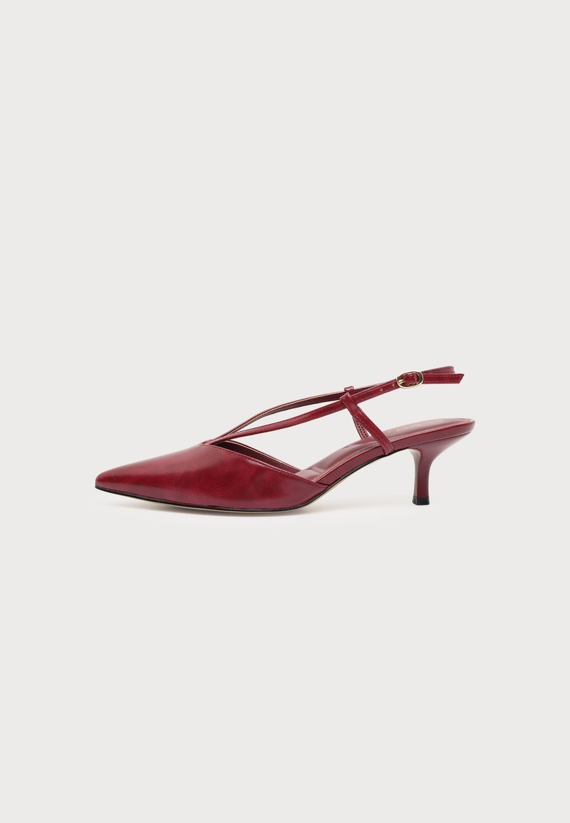 Chaussure slingback rouge en cuir à bout pointu avec fines brides et petit talon kitten sur fond blanc.