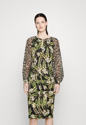 Μαύρο φόρεμα με μοτίβο πράσου φύλλων και λευκών λουλουδιών, με διαφανείς μανίκες λεοπαρντί και στρογγυλή λαιμόκοψη με λεπτομέρεια σε σχήμα κλειδώματος.