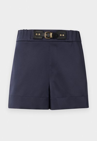 Σκούρο μπλε σορτς με ψηλή μέση και μαύρη ζώνη με αγκράφα που διαθέτει χρυσά μεταλλικά στοιχεία, σε απλό ανοιχτό φόντο.