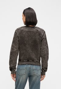 Σκούρο γκρι φούτερ με ριμπ μανσέτες και τελείωμα, με ξεθωριασμένη υφή και αντίθετες ραφές κατά μήκος των ραφών των ώμων.