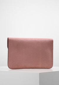Clutch de sobre en imitación cuero rosa con una textura suave, forma rectangular y cierre de solapa, descansando sobre una superficie blanca.