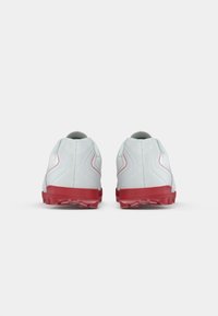 Zapatillas deportivas blancas con suelas y detalles rojos, con una parte superior texturada y un diseño redondeado. Adecuadas para diversas actividades deportivas.