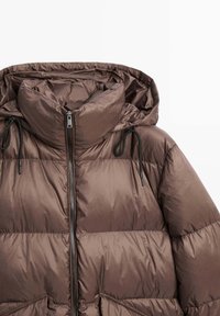 Giacca invernale imbottita marrone con cappuccio, zip frontale e cordini neri su sfondo bianco.