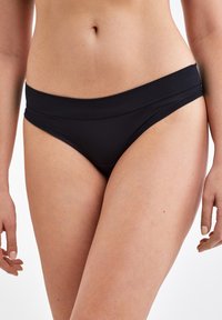 Bas de bikini noir avec une texture lisse, taille moyenne et design épuré. Présente une couture minimale et une coupe simple.