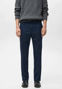 Pantaloni de dressing bleumarin cu dungi fine, cu croi drept, talie ajustată și textură subtilă, asortați cu pantofi negri de dressing și un pulover gri.