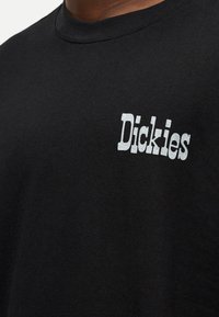Μαύρο βαμβακερό t-shirt με στρογγυλή λαιμόκοψη και κοντά μανίκια. Διαθέτει λευκό εκτυπωμένο λογότυπο «Dickies» στην αριστερή πλευρά του στήθους.