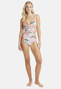 Maillot de bain une pièce avec un motif floral coloré, présentant un décolleté en V profond, des bretelles larges et des détails froncés à la taille.