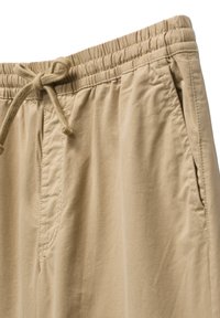 Beige stretching bukser med elastisk talje og snøre, der har en glat overflade og sidelommer. Rene stikninger.