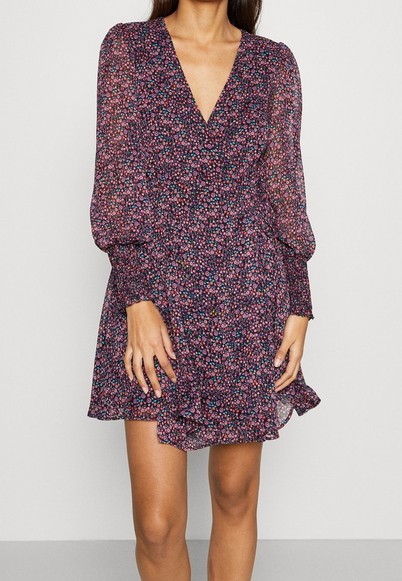 Robe courte fleurie en chiffon violet foncé avec manches longues bouffantes et profond décolleté en V. Présente un ourlet à volants et un motif floral multicolore vibrant.
