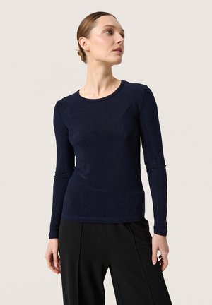 Navy long-sleeve top made of shimmery fabric, featuring a round neckline and fitted silhouette, paired with black wide-leg pants.