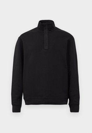 Sort langærmet pullover med høj krave og kort lynlåsåbning, ribbede manchetter og kant, præsenteret på en ensfarvet lys baggrund.