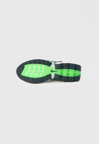Potplat Nike atletskih cipela s vanjskim dijelom od crne gume, zelenim srednjim dijelom i bijelim akcentima, s teksturiranim gripom i elementima zračne amortizacije.