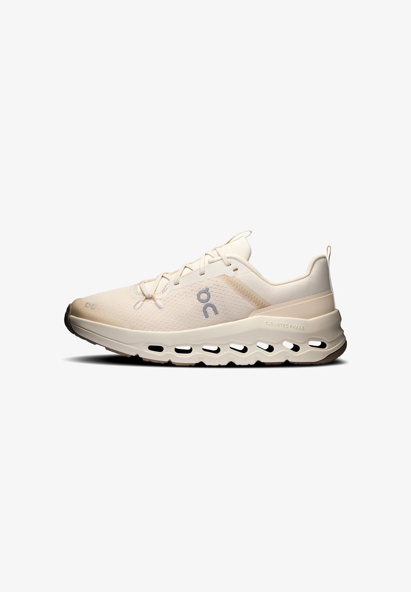 Chaussure de course beige clair avec tige en mesh, fermeture à lacets, semelle amortissante avec design CloudTec et logo sur le côté.