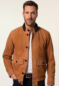 Bruine suède jas met een drukknoopsluiting, contrasterende donkere kraag, twee frontzakken en een ontspannen pasvorm.