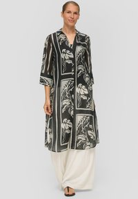 Schwarzes und weißes langes Kurta mit floralen Mustern, Knopfverschluss und drei Viertel Ärmeln. Getragen über cremefarbenen lockeren Hosen.