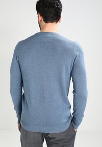 Maglione blu lavorato a maglia con maniche lunghe, scollatura rotonda e orlo a coste. Texture morbida e design aderente.