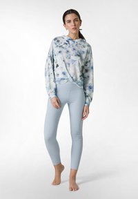 Ljust blått tie-dye sweatshirt med långa ärmar, parat med blekblå leggings. Outfitten har en avslappnad passform och mjuk, slät textur.