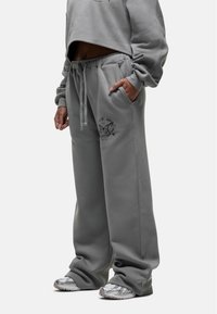 Grijze sweatshirt met een cropped design, lange mouwen; bijpassende losse grijze sweatpants met een trekkoord en vlinder grafiekdetail.