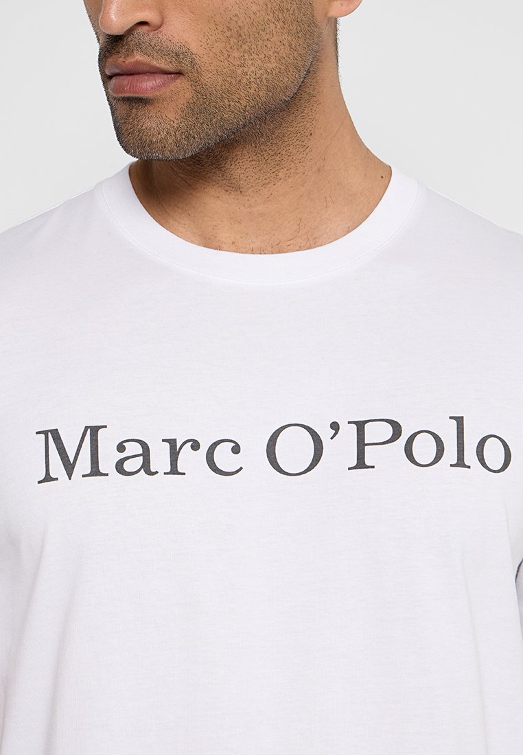 Weißes Baumwoll-T-Shirt mit einem auffälligen schwarzen Druck von "Marc O'Polo" über der Brust. Rundhalsausschnitt und kurze Ärmel.