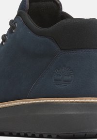 Zapatillas de ante azul marino con detalles en negro y suela de goma; cuentan con costuras decorativas y un logo en relieve en el lateral.
