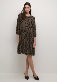 Rochie maro cu imprimeu leopard negru, mâneci lungi, închidere cu nasturi și fustă în straturi. Material texturat cu un design fluid.